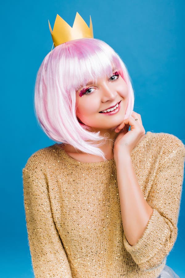 Jeune femme gaie de portrait avec les cheveux roses coupés, dans le chandail et la couronne d'or sur le chef souriant à la caméra photos libres de droits Jeune femme gaie de portrait avec les cheveux roses coupés, dans le chandail et la couronne d'or sur le chef souriant à la caméra photos libres de droits
