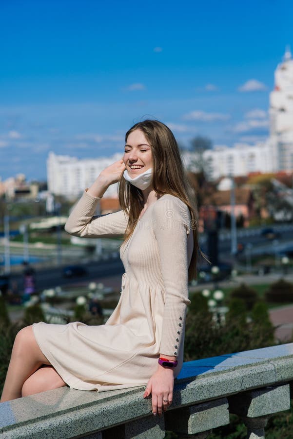 Happy cheerful young woman removing face medical mask while standing on street. Happy cheerful young woman removing face medical mask while standing on street