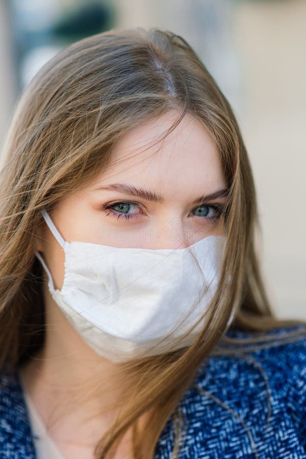 Happy cheerful young woman removing face medical mask while standing on street. Happy cheerful young woman removing face medical mask while standing on street