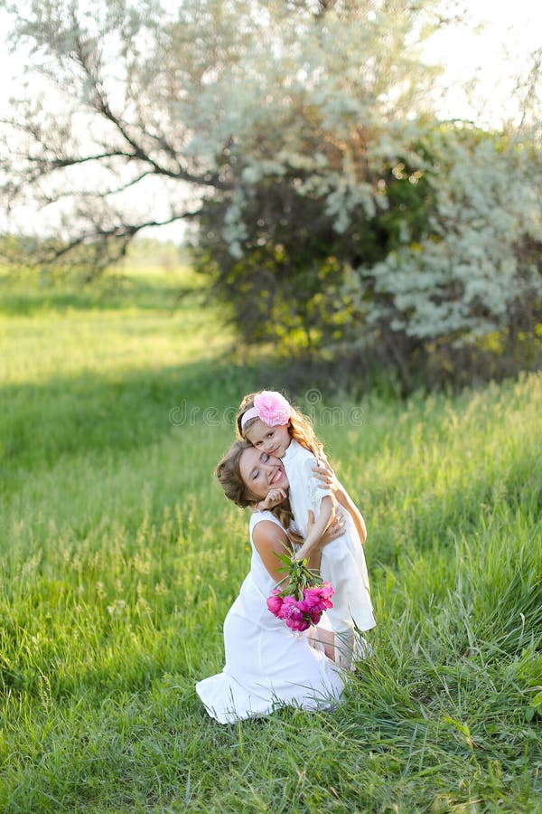 Jeune femme heureuse assise avec petite fille sur l'herbe. photographie stock libre de droits