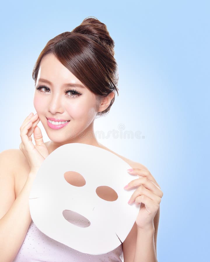 Happy Young woman with cloth facial mask isolated on blue background, concept for skin care, asian. Happy Young woman with cloth facial mask isolated on blue background, concept for skin care, asian