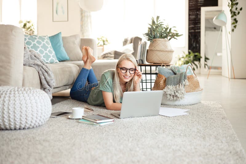 Jeune femme heureuse détendant à la maison et à l'aide de l'ordinateur portable
