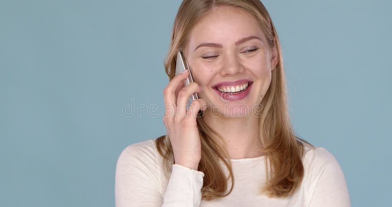 Jeune femme heureuse mignonne parlant avec quelqu'un sur son portable. Isolé sur un bleu