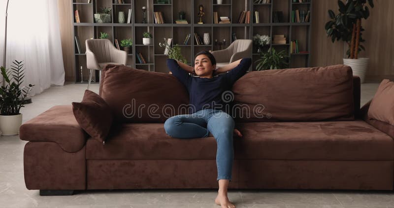 Jeune femme indienne métisse reposant sur un canapé confortable. banque de vidéos