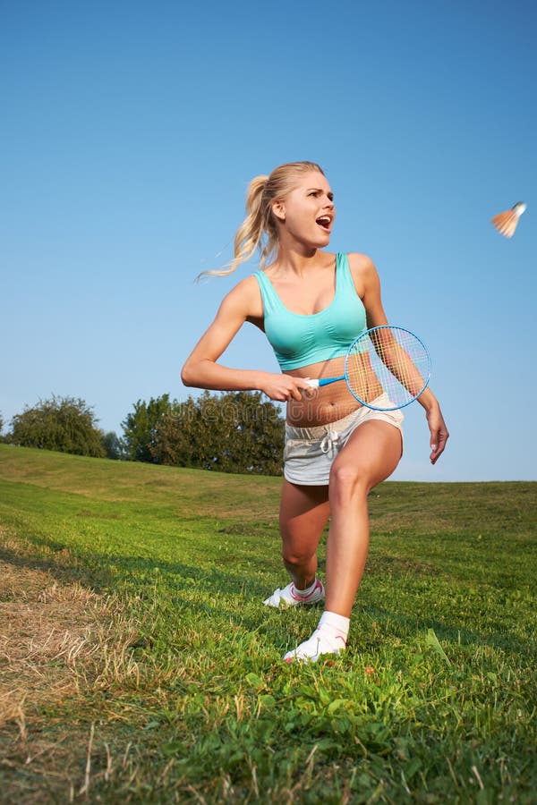 Jeune femme jouant le badminton en parc de ville image stock Jeune femme jouant le badminton en parc de ville image stock