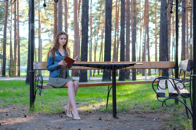 Jeune femme lisant un livre et détendant au parc image libre de droits Jeune femme lisant un livre et détendant au parc image libre de droits