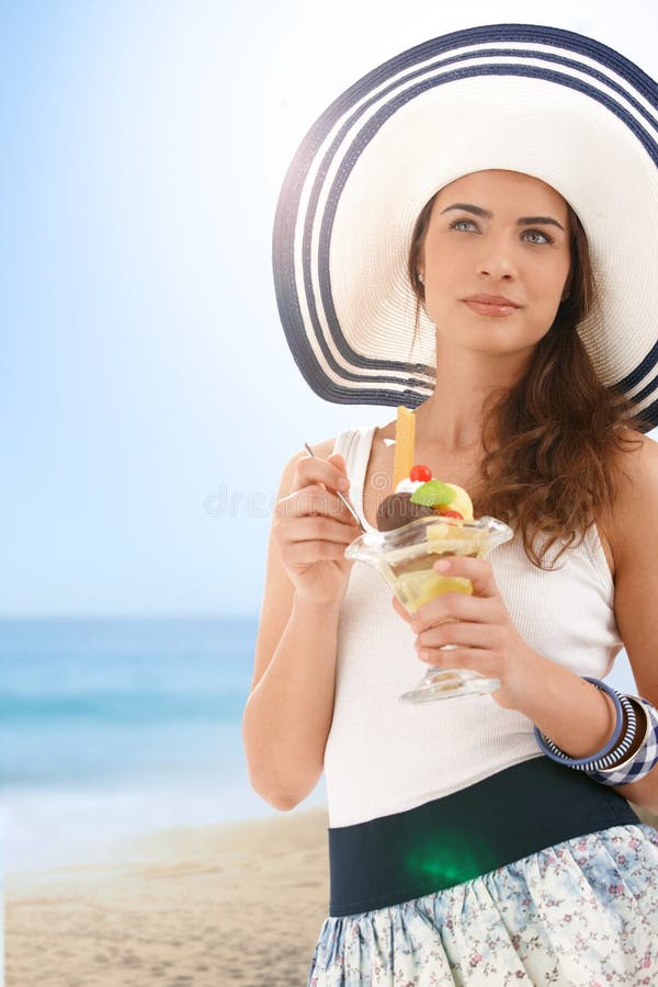 Jeune femme mangeant de la glace sur la plage d'été image libre de droits Jeune femme mangeant de la glace sur la plage d'été image libre de droits