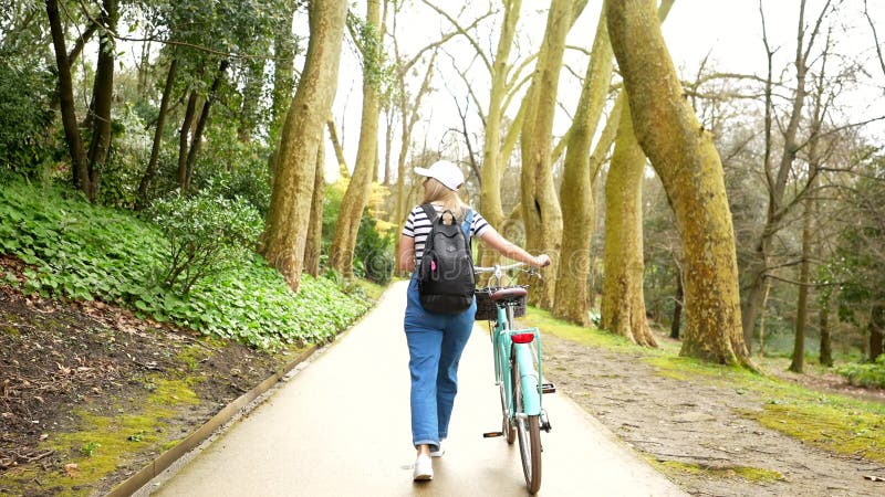 Jeune femme marchant à vélo dans le parc clips vidéos