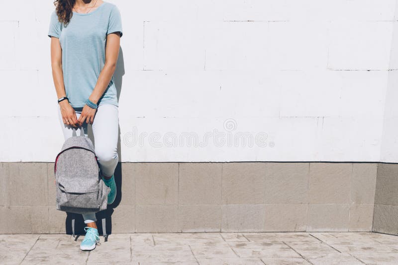 Jeune femme mince dans les jeans et le T-shirt se tenant contre W blanc photo stock Jeune femme mince dans les jeans et le T-shirt se tenant contre W blanc photo stock
