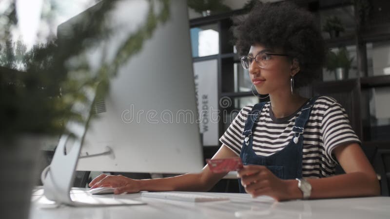 Jeune femme mixte acheter en ligne avec la carte de crédit à l'aide de l'ordinateur portable pour siéger à l'intérieur. Achats à l banque de vidéos