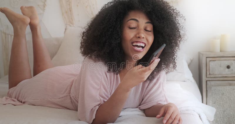 Jeune femme mixte souriante enregistrant un message audio à un ami à l'aide d'un smartphone banque de vidéos