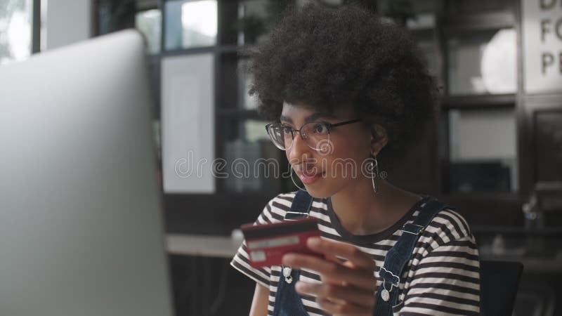 Jeune femme mixte tenant la carte de crédit et les achats en ligne. Salaire facile en utilisant l'instrument numérique. Fille à l' banque de vidéos