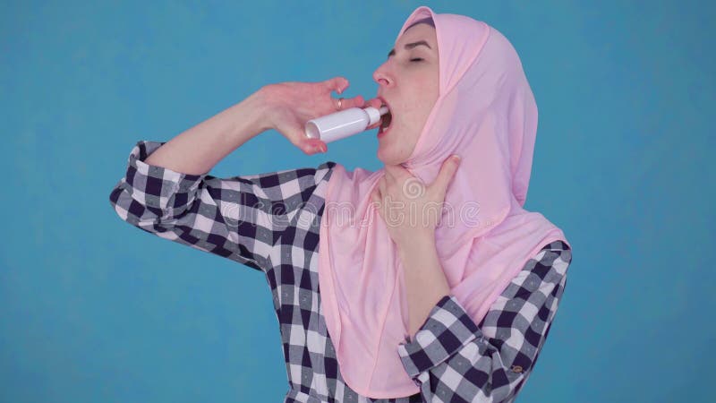 Jeune femme musulmane dans le hijab ayant des ennuis avec l'angine, jet d'utilisations traiter la gorge clips vidéos