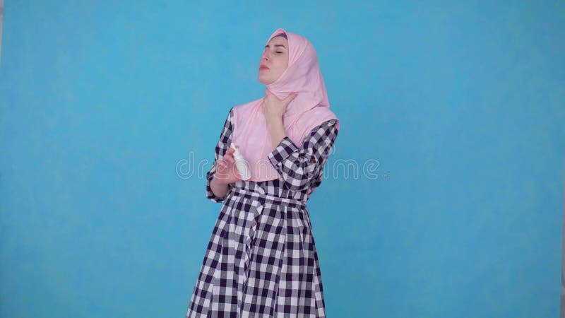 Jeune femme musulmane dans le hijab ayant des ennuis avec l'angine, jet d'utilisations traiter la gorge clips vidéos