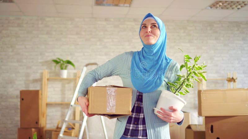 Jeune femme musulmane de portrait dans un hijab avec une fleur et une boîte dans des ses mains banque de vidéos