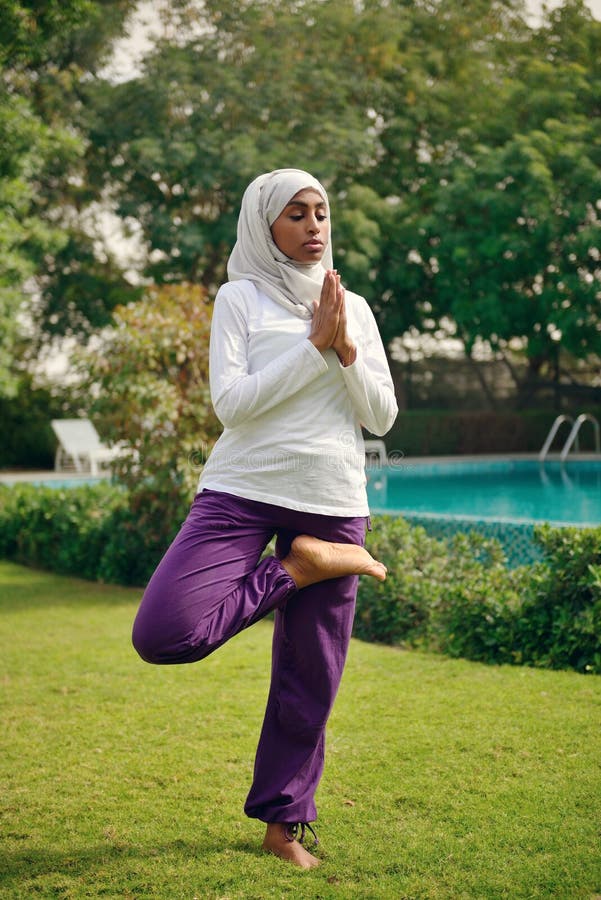 Jeune femme musulmane faisant le yoga par le poolside images stock Jeune femme musulmane faisant le yoga par le poolside images stock