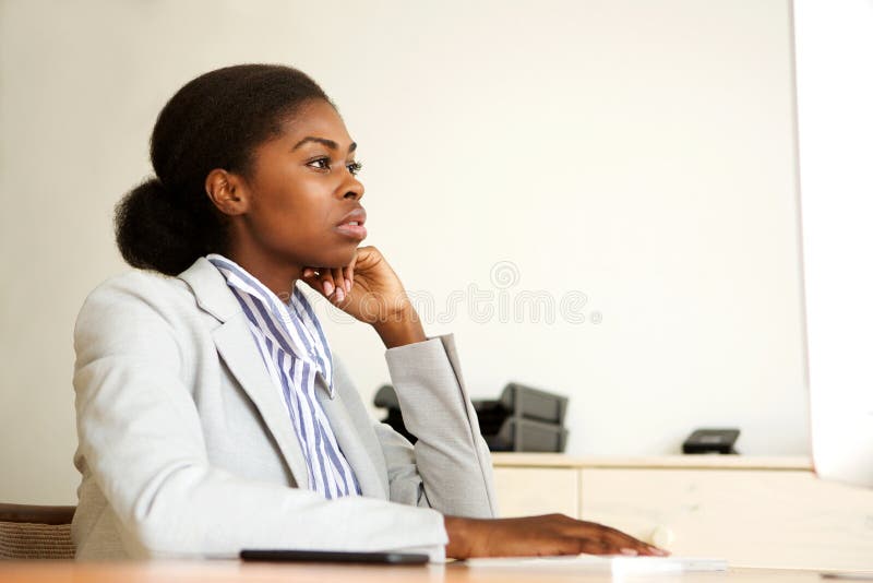Jeune femme noire sérieuse d'affaires s'asseyant dans le bureau regardant l'écran d'ordinateur photos libres de droits