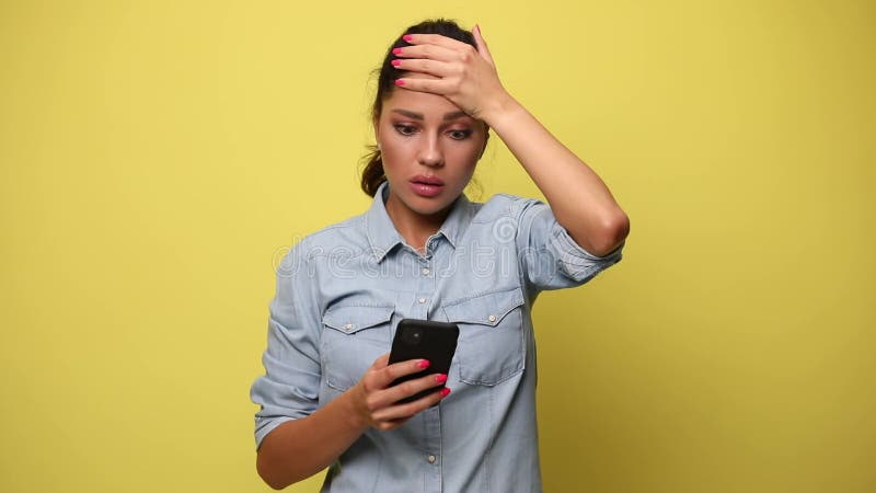 Jeune femme occasionnelle dans la chemise bleue de denim sur le fond jaune