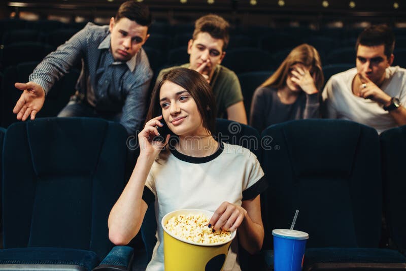 Jeune femme parlant par le téléphone dans le cinéma images stock Jeune femme parlant par le téléphone dans le cinéma images stock