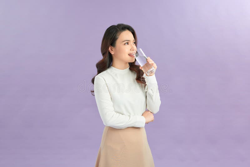Jeune femme posant sur fond studio isolé tenir le verre d'eau photo libre de droits