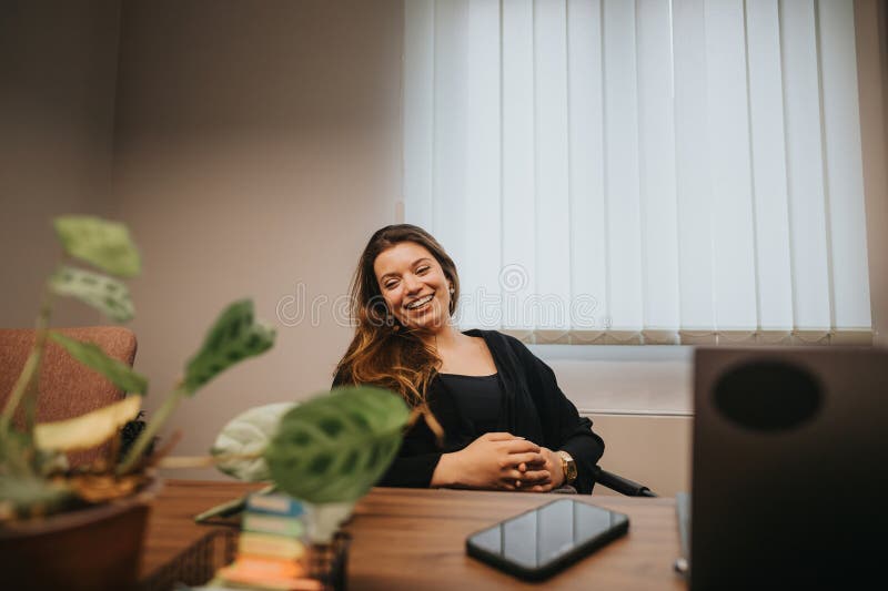 A cheerful young female professional enjoys a brief relaxing moment at her office desk, surrounded by indoor plants and modern office decor. A cheerful young female professional enjoys a brief relaxing moment at her office desk, surrounded by indoor plants and modern office decor.