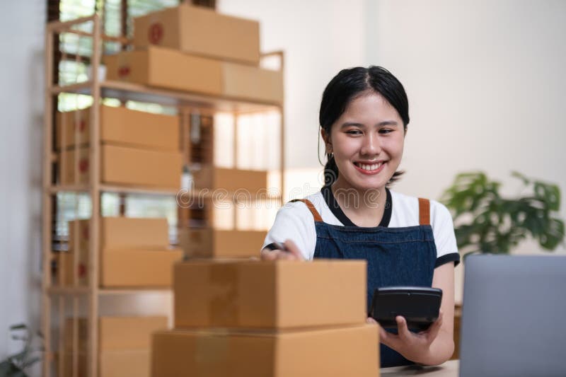 Young woman, small business owner selling products online, accepting online product orders via laptop, sits in a room with boxes of products. Young woman, small business owner selling products online, accepting online product orders via laptop, sits in a room with boxes of products..