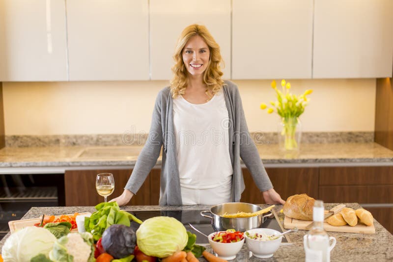 Jeune femme préparant la nourriture dans la cuisine moderne images stock Jeune femme préparant la nourriture dans la cuisine moderne images stock