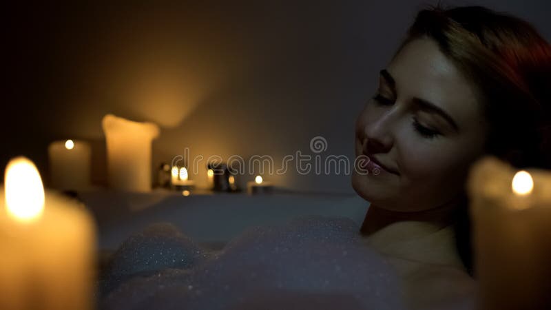 Jeune femme qui se baigne avec des bulles de mousse et des bougies, le soir, se détendre, fermer-la photos libres de droits Jeune femme qui se baigne avec des bulles de mousse et des bougies, le soir, se détendre, fermer-la photos libres de droits