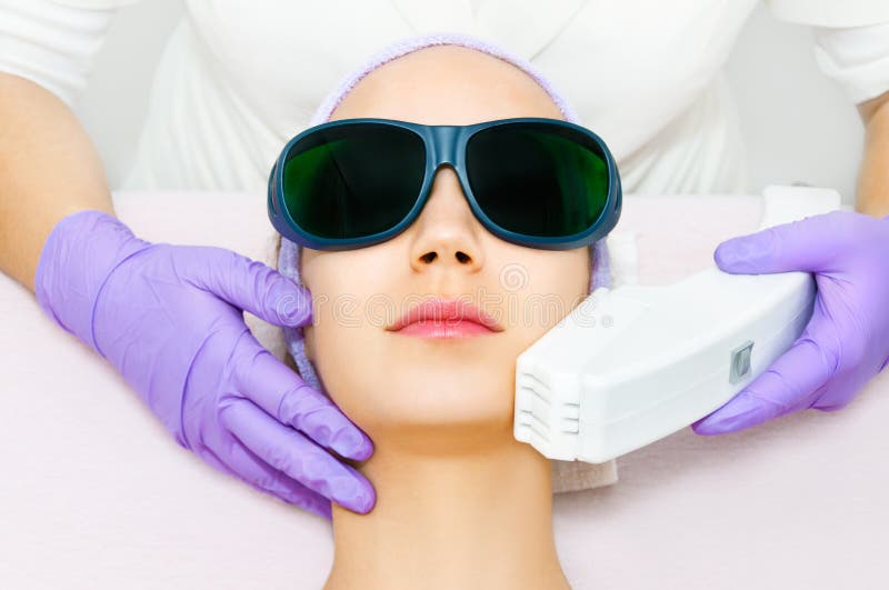 Jeune femme recevant le traitement de laser d'epilation image stock Jeune femme recevant le traitement de laser d'epilation image stock