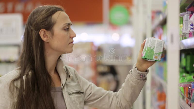 Jeune femme regardant des marchandises d'une hygiène dans le supermarché