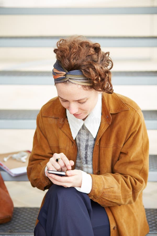 Jeune femme rousse de hippie à l'aide du smartphone images stock Jeune femme rousse de hippie à l'aide du smartphone images stock