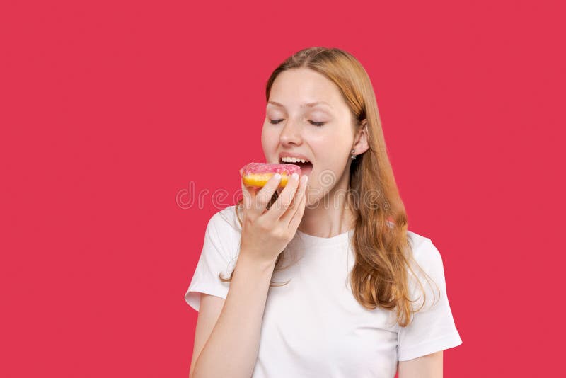 Jeune femme s'amuser et manger de la malbouffe beignets doux portant un tshirt blanc images stock