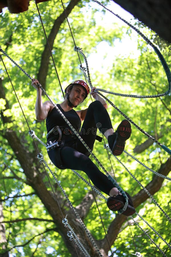 Jeune femme s'élevant en parc de corde d'aventure image libre de droits Jeune femme s'élevant en parc de corde d'aventure image libre de droits