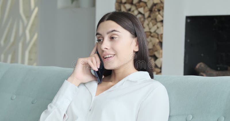 Jeune femme se relaxer sur un canapé confortable en écoutant de la musique lounge en direct via l'application smartphone banque de vidéos