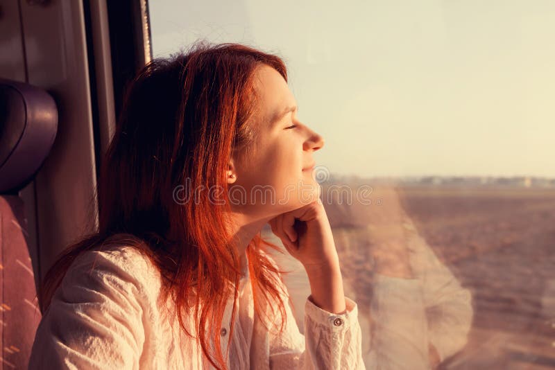 Jeune femme sentant le déplacement décontracté près de la fenêtre de train photo stock