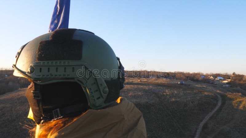 Jeune femme soldat en camouflage uniforme levant drapeau d'ukraine. une femme de l'armée ukrainienne se tient au sommet de la coll clips vidéos