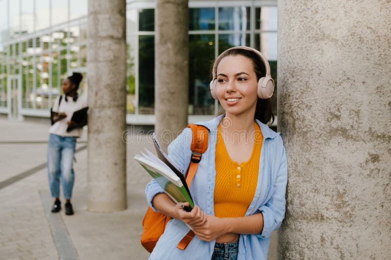 Jeune femme souriant et écoutant de la musique debout en construisant image stock