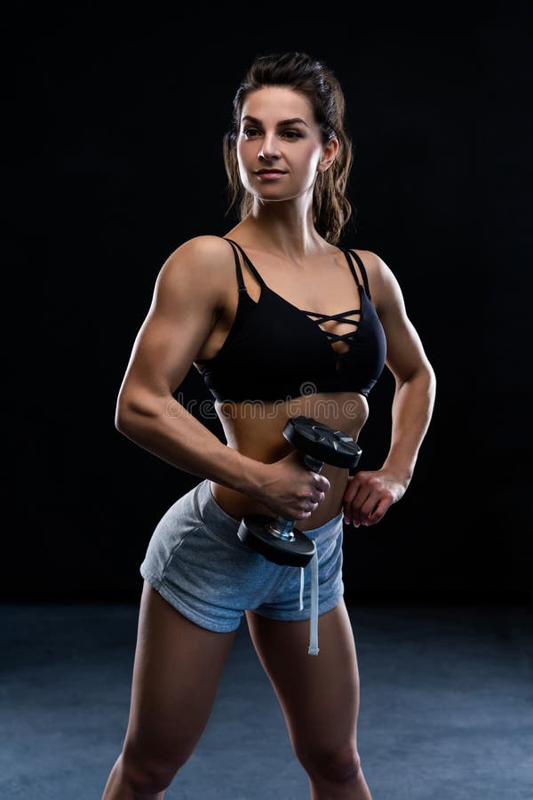 Jeune femme sportive faisant une séance d'exercice de remise en forme avec des haltères sur le fond noir de studio photo stock