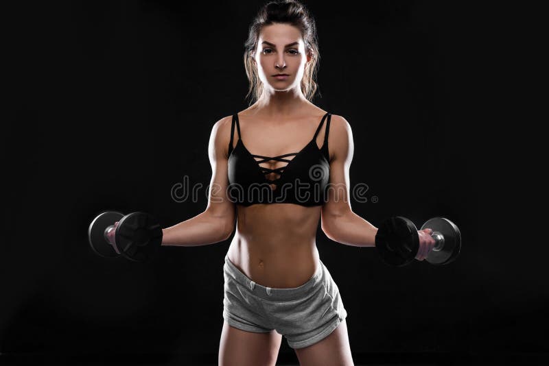 Jeune femme sportive faisant une séance d'exercice de remise en forme avec des haltères sur le fond noir de studio photo stock