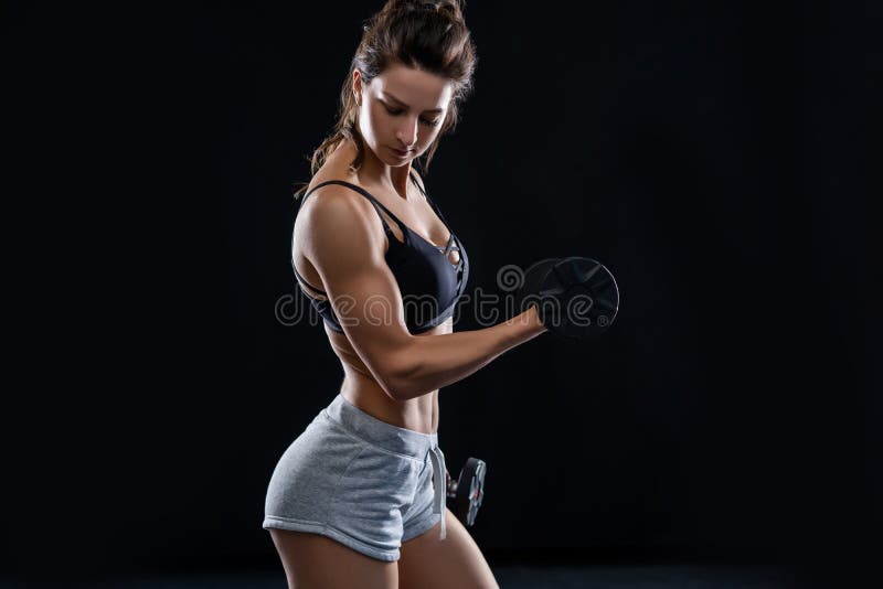 Jeune femme sportive faisant une séance d'exercice de remise en forme avec des haltères sur le fond noir de studio image libre de droits