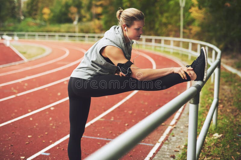 Jeune femme sportive s'étirant sur le stade photographie stock libre de droits Jeune femme sportive s'étirant sur le stade photographie stock libre de droits