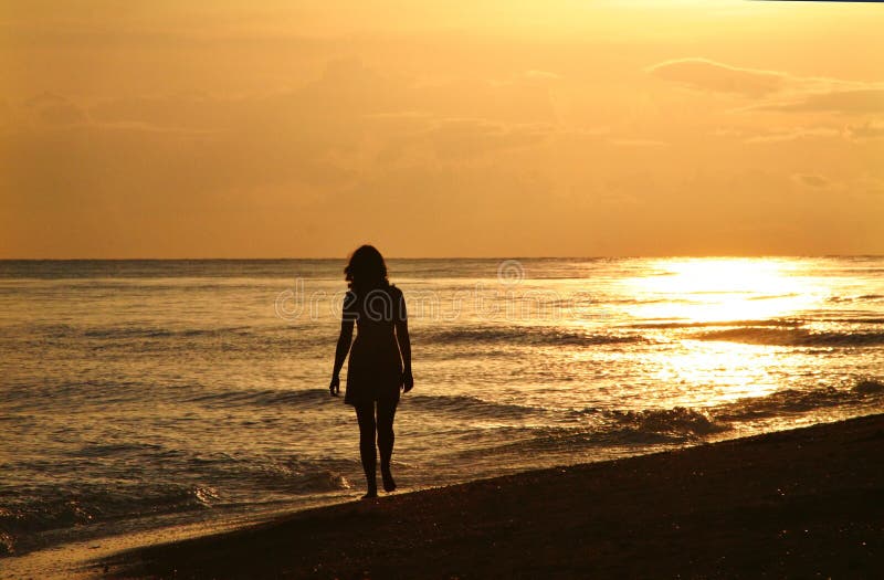 A young woman taking a walk on the beach at sunset. A young woman taking a walk on the beach at sunset
