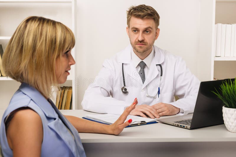 Jeune femme sur une consultation avec un chirurgien ou un thérapeute masculin dans son bureau photographie stock libre de droits Jeune femme sur une consultation avec un chirurgien ou un thérapeute masculin dans son bureau photographie stock libre de droits