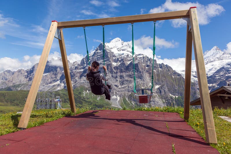 Jeune femme sur une oscillation, balançant au-dessus des montagnes, Grindelwald image libre de droits Jeune femme sur une oscillation, balançant au-dessus des montagnes, Grindelwald image libre de droits