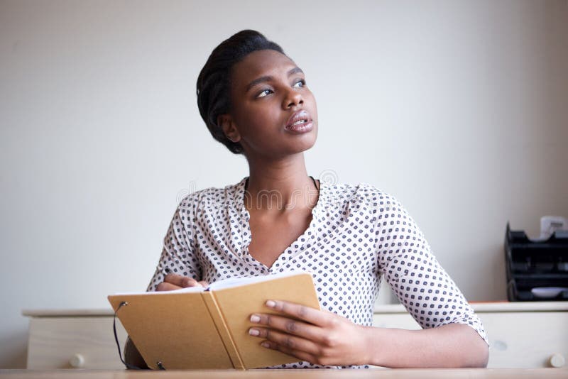 Jeune femme sérieuse pensant et écrivant en journal image libre de droits