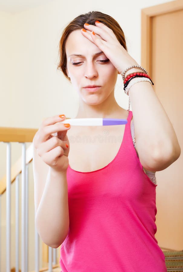 Jeune femme sérieuse triste avec l'essai de grossesse photos stock Jeune femme sérieuse triste avec l'essai de grossesse photos stock