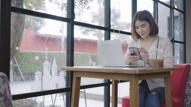 Jeune femme utilisant smartphone vérifier les médias sociaux sur internet dans le café souriant heureux clips vidéos