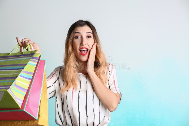 Jeune femme étonnée avec des sacs à provisions sur le fond clair image libre de droits Jeune femme étonnée avec des sacs à provisions sur le fond clair image libre de droits