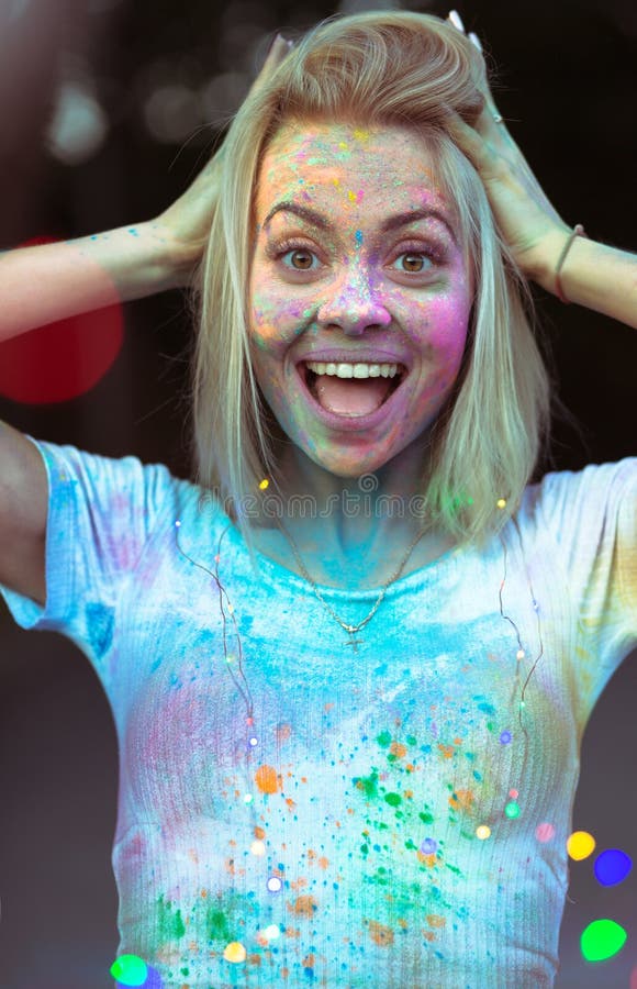 Jeune femme étonnée avec la peinture de Holi sur son visage posant avec la Co images libres de droits Jeune femme étonnée avec la peinture de Holi sur son visage posant avec la Co images libres de droits