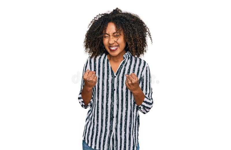 Jeune fille afro-américaine portant des vêtements décontractés excité pour le succès avec les bras levés et les yeux fermés célébr photos stock